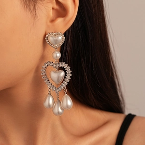 Close-up of double heart pearl earrings with sparkling zircons worn by a model