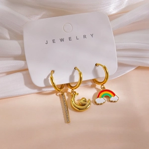 Detail view of 14K gold-plated hoop earrings with moon, heart, and rainbow charms on a card