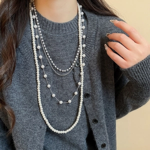 Detail of layered white pearl necklace with delicate silver chains on model