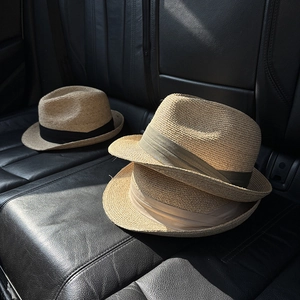 Classic unisex straw fedora hats in tan and beige on a leather seat for travel
