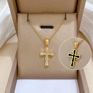 Macro detail of gold cross pendant with zircon stones and black enamel reverse finish