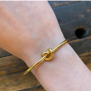 Dettaglio del bracciale annodato in acciaio al titanio placcato oro 18K su un polso vero