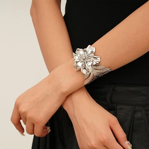 Detail of a large silver floral cuff bracelet featuring layered 3D metal petals and textures