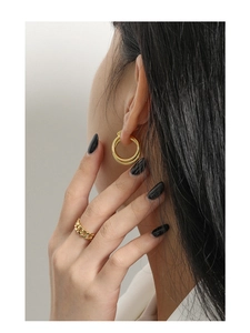 Detail of layered gold-tone hoops and cuban link ring on a fashion model