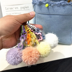 Colorful plush ball keychain with acrylic chain and flowers on a denim bag