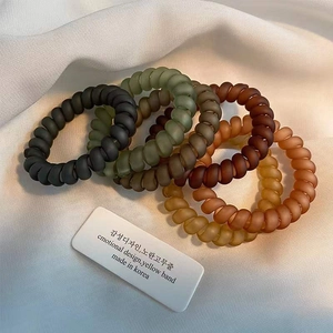 Detailed view of matte spiral phone cord hair ties in earthy Morandi color palette