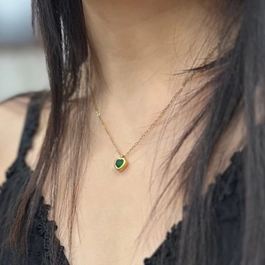 Close-up of heart-shaped green gemstone necklace on gold chain around model's neck