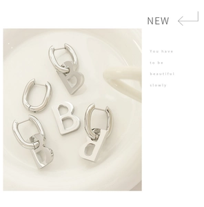 Close-up of silver geometric B-shaped earring with S925 hallmark on white plate