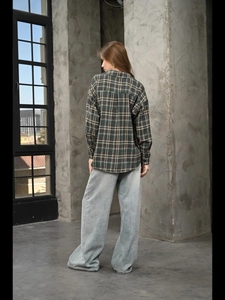 Back view of a loose-fit dark green plaid long-sleeve shirt with wide-leg jeans