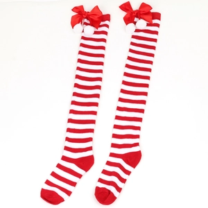 Detail of Christmas over-knee socks with red-white stripes, bows and pom-poms