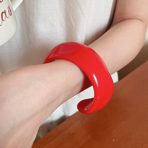 Detailed close-up of a stylish red resin open cuff bracelet with a wrinkled texture design