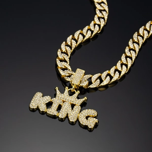 Macro view of gold-plated KING pendant with crown and iced-out rhinestones on cuban link chain