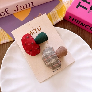 Detail of two handmade plush mushroom hair clips in plaid and polka dot patterns