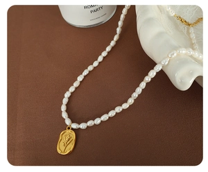 Detail of freshwater pearl necklace featuring a golden tulip relief oval pendant