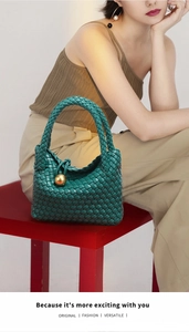 Detailansicht der dunkelgrünen Leder Handtasche mit edler Goldkugel und klassischem Flechtwerk.