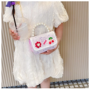 Fille en robe blanche portant un sac en tweed lilas avec poignée en perles et des sequins