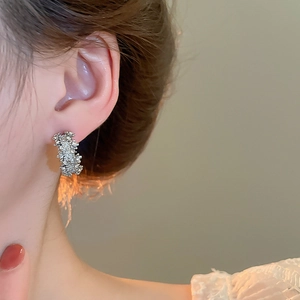 Gros plan d'une boucle d'oreille argentée en forme de C avec texture de lave fondue