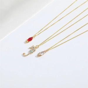 Minimalist gold chain necklaces featuring red marquise gem and seahorse crystal pendants