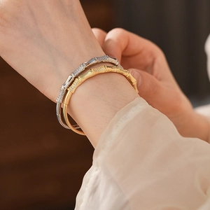 Close-up of gold and silver bamboo-style bracelets with sparkling zircons on a wrist