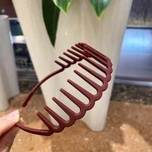 Close-up of a matte wine red wavy toothed headband for securing hair texture