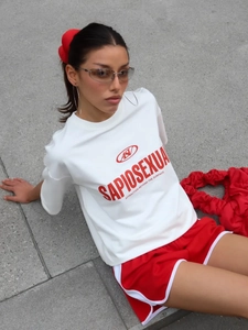Λεπτομέρεια από λευκό βαμβακερό T-shirt με τύπωμα Sapiosexual και κόκκινο αθλητικό σορτς