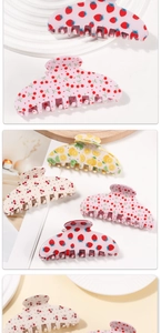 Detailed view of hair clips with strawberry, cherry, and lemon fruit patterns on a tray