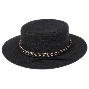 Detail of black woven straw hat featuring a bold gold chain and ribbon band decoration