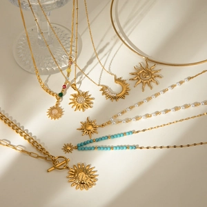 Golden stainless steel sun pendant necklaces with pearls and colorful gemstones in soft light