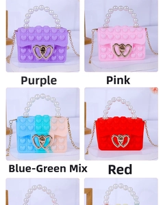 Detail of colorful silicone pop-it heart bags with pearl handles and metal chain straps