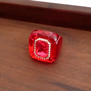 Detail shot of vintage red resin ring with crystal inlay on a walnut wood display