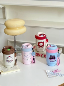 Detail of four colorful stainless steel coffee mugs with silicone straps in home setting