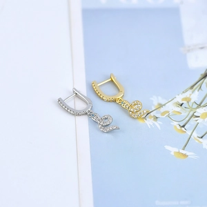 Macro detail of snake-shaped earrings in gold and silver with sparkling cubic zirconia