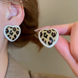 Close-up of leopard print heart earrings with white enamel border and silver needles