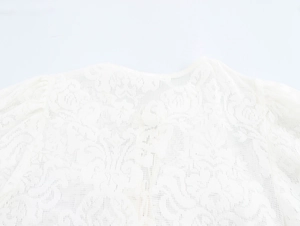 Close-up of white lace blouse featuring delicate floral hollow embroidery and neckline detail