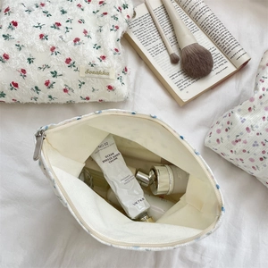 Vue détaillée de dessus d'une trousse à maquillage fleurie avec fermeture éclair en métal