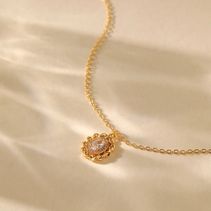 Close-up of 18K gold fan necklace with oval pendant and sparkling clear zircon center