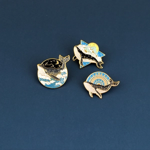 Set of 3 minimalist whale enamel pins with navy blue and gold metal wave designs