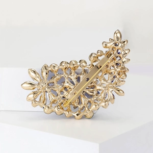 Close-up of golden vintage alloy brooch back with blue gemstone and secure pin clasp