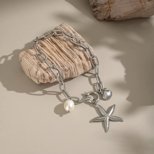 Détail des breloques étoile de mer et coquillage argentées avec perle sur le bracelet