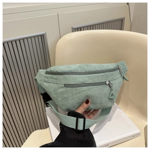Close-up of light green corduroy waist bag with adjustable strap and buckle closure