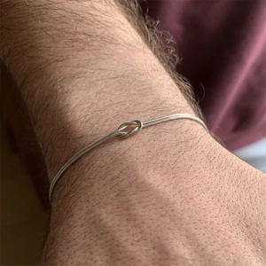 Macro shot of silver stainless steel knot snake chain bracelet worn on a female wrist