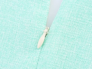 Detail of light green tweed fabric featuring a matching teardrop invisible zipper