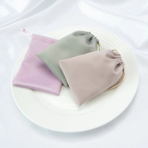 Detailed close-up of purple, green and pink satin drawstring jewelry pouches on a tray