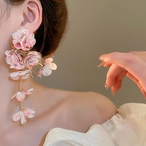 Close-up of long chiffon fabric flower tassel earrings worn by a model in soft lighting