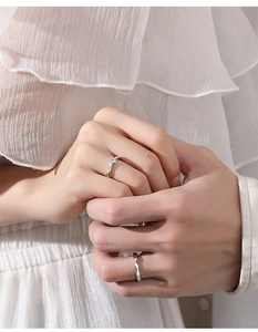 Close-up of couple's silver wave rings with a sparkling diamond on the woman's band