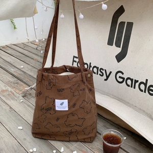 Macro detail of brown corduroy tote bag with bear print and soft ribbed texture