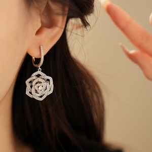 Close-up of silver hollow rose earring with sparkling cubic zirconia on model