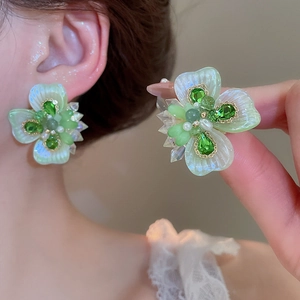 Detailed view of light green crystal flower earrings with sparkling rhinestone center