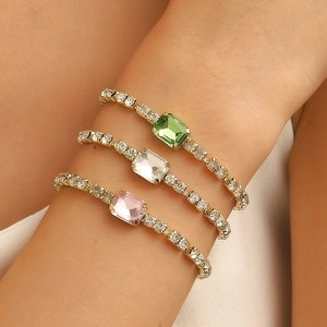 Elegant gold Cuban link bracelet with emerald green zircon stone worn on a female wrist