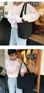 Détail du sac cabas en toile noire porté avec un sweat blanc et un jean bleu clair